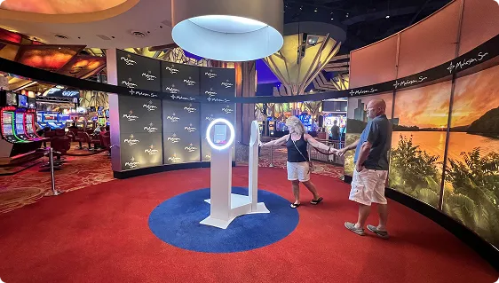 OutSnapped booth at high-end entertainment venue FutoRover 360 photo booth with illuminated blue circular base in upscale casino lobby, guests interacting nearby