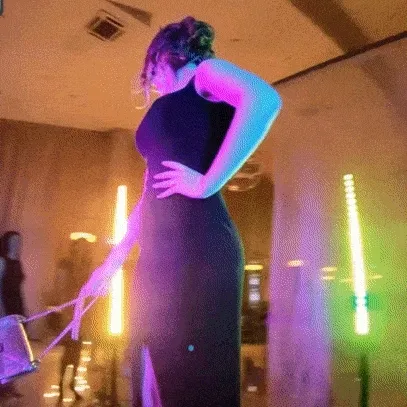 Woman posing in 360 video booth with neon lighting effects in purple, pink, and cyan