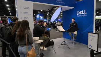 Corporate Event Headshot Booth Activation Professional headshot setup at trade show with Dell branding, featuring photographer, subject in chair, lighting equipment, and booth visitors