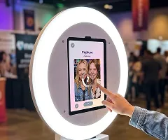 Hand touching screen of FotoRover AI video booth with illuminated ring light at event venue
