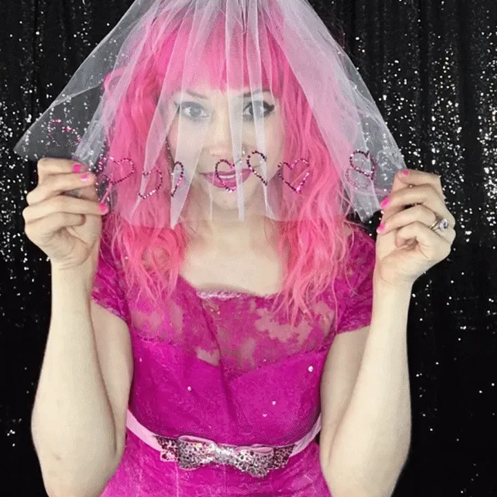 Glamorous Pink Outfit Boomerang Photo Tips Woman in magenta sequin dress and pink wig holding sheer veil with heart-shaped cutouts, demonstrating dynamic movement for boomerang video content