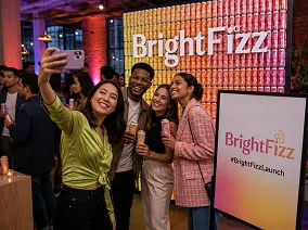 Mobile photo booth at brand activation event Woman in yellow-green top taking selfie with guests at BrightFizz brand activation event