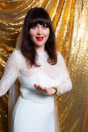 Bride in white long-sleeve dress against gold sequined backdrop