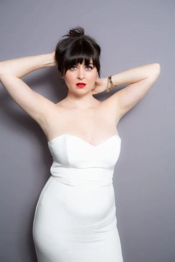 Woman in white strapless gown with arms posed behind head