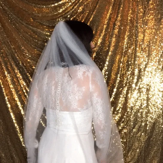 Bride in white dress and veil against gold sequin backdrop