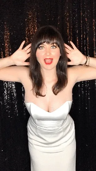 Woman in white dress with playful pose against sparkly black backdrop
