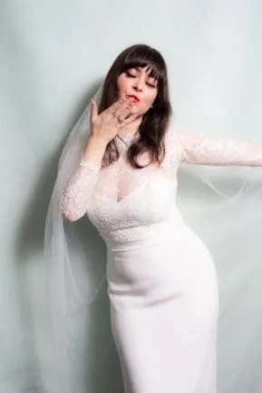 Bride in white wedding dress with veil against soft backdrop