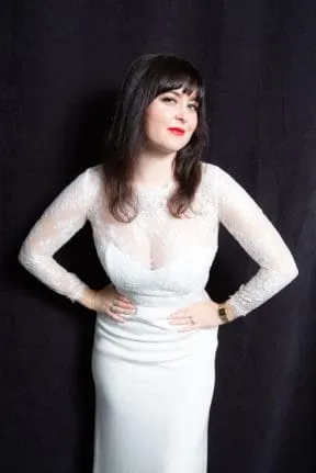 Woman in white dress against dark backdrop