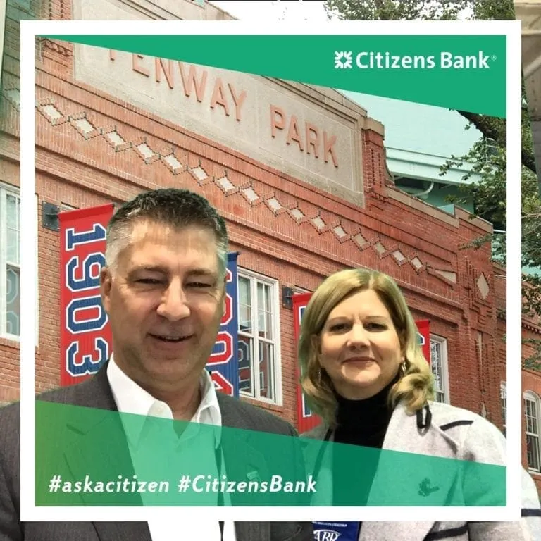 Two business professionals posing in Citizens Bank branded photo booth at trade show