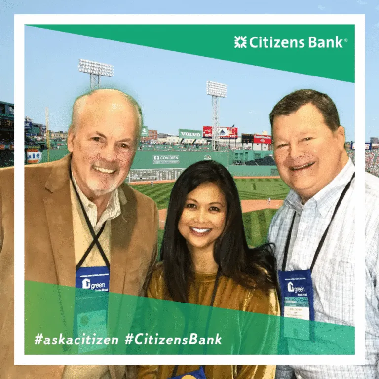 Three attendees smile at Citizens Bank trade show booth with Fenway Park visible in background