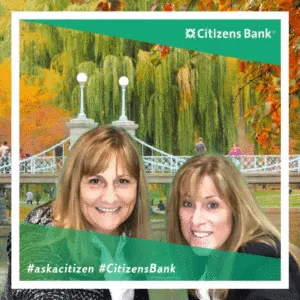 Two smiling women in Citizens Bank trade show photo booth frame with garden backdrop and white bridge, branded with Citizens Bank logo and #askacitizen #CitizensBank hashtags