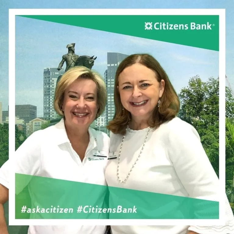 Two women in white outfits smiling at Citizens Bank trade show photo booth with Boston skyline backdrop
