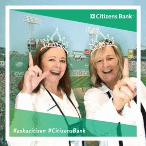 Two women wearing tiaras and smiling at Citizens Bank trade show photo booth with baseball stadium backdrop