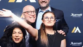 Four people smiling at a FutureFoto photo booth with Marriott branding visible in background