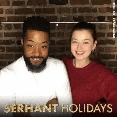 Couple smiling at holiday photo booth against brick wall