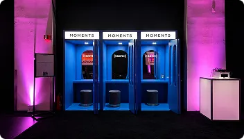 Premium Event Photo Booth Setup Three blue FutoRover roaming photo booths lined up in a dark venue with magenta accent lighting and branded signage