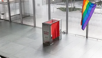 Professional Lobby Photo Booth Installation FutureFoto open-air photo booth in red installed in a modern lobby with glass walls and pride flag