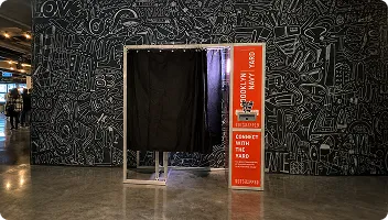 Photo Booth Installation in Modern Gallery FutureFoto open-air photo booth with black frame and orange branding installed in a modern retail space with geometric wall art