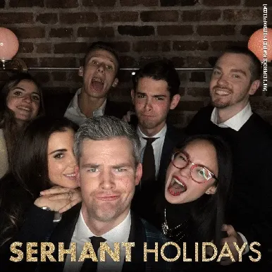 Group of people posing with varied expressions at holiday photo booth