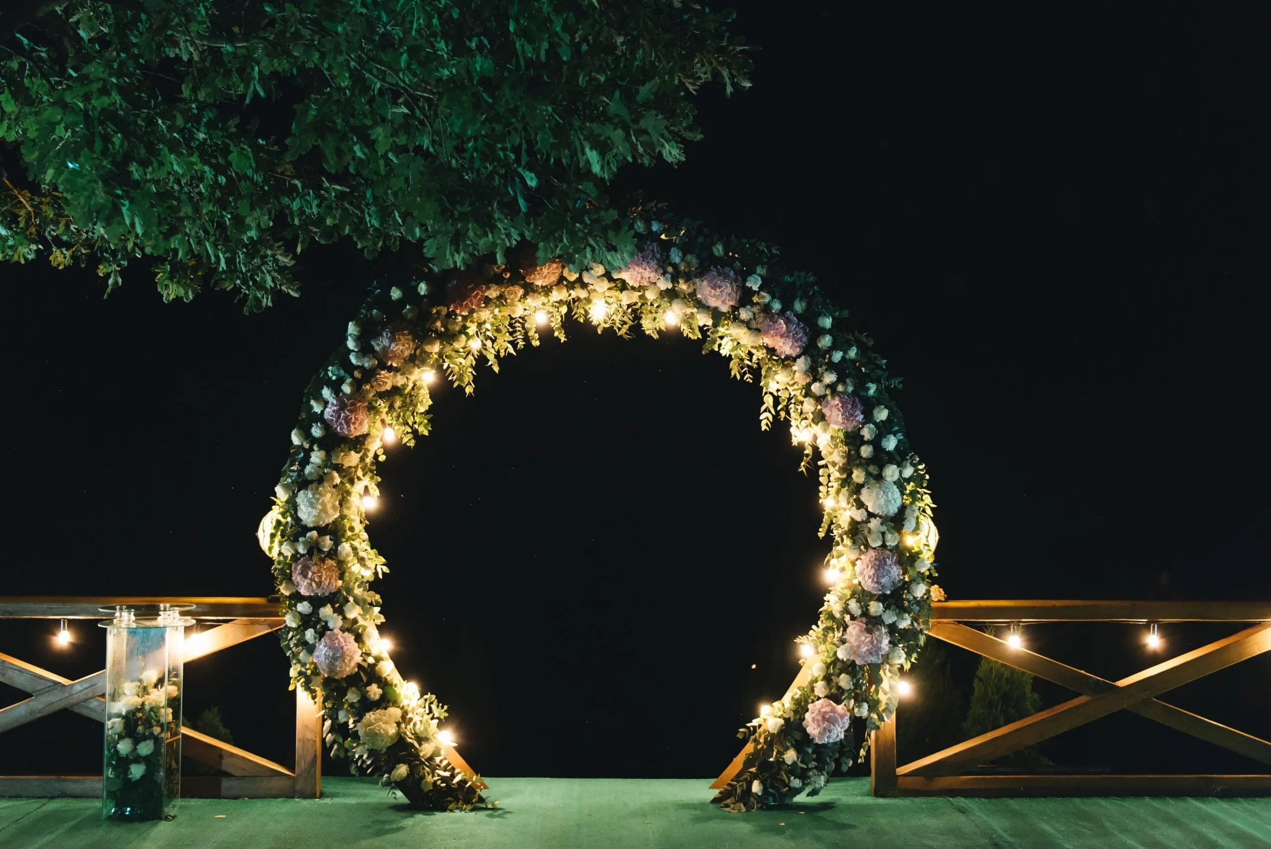 Lit Floral Arch Photo Booth Backdrop Illuminated circular floral arch at night with white and blush flowers