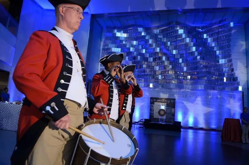 Live Performance Entertainment at Museum Event Museum performers in formal red and white attire playing percussion with digital cityscape projection backdrop