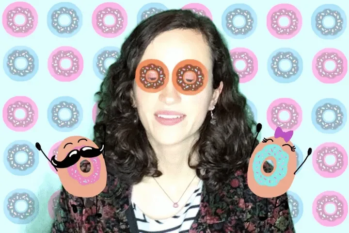AI donut photo booth filter portrait Woman with black wavy hair wearing donut-shaped sunglasses and holding pink and blue frosted donuts, with colorful donut pattern backdrop