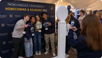 Alumni groups posing at white circular mirror photo booth during Northridge University Homecoming 2026