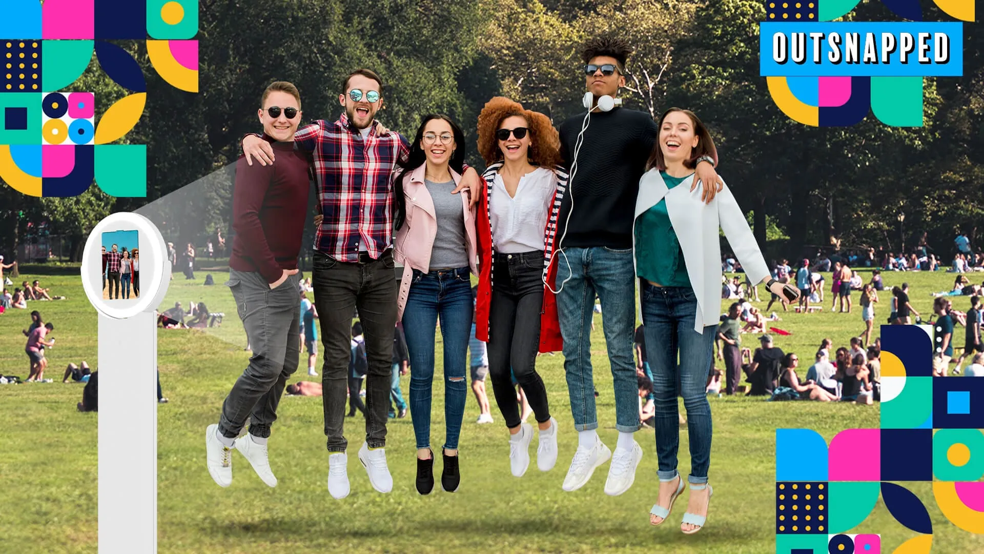 Group of seven people jumping in the air together in Central Park with trees and other park visitors in the background, with OutSnapped branding visible