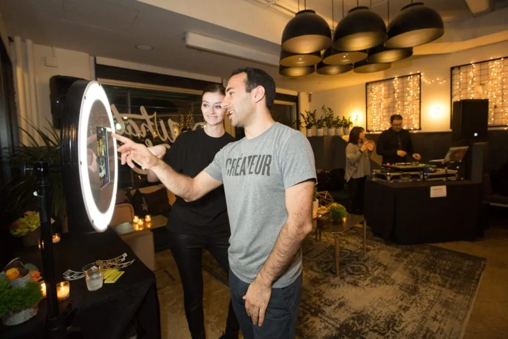 Couple using interactive photo booth mirror with glowing circular display at party event