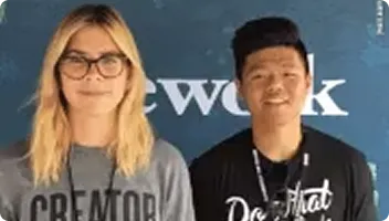 Two people smiling at a photo booth activation, wearing lanyards at what appears to be a corporate event or trade show