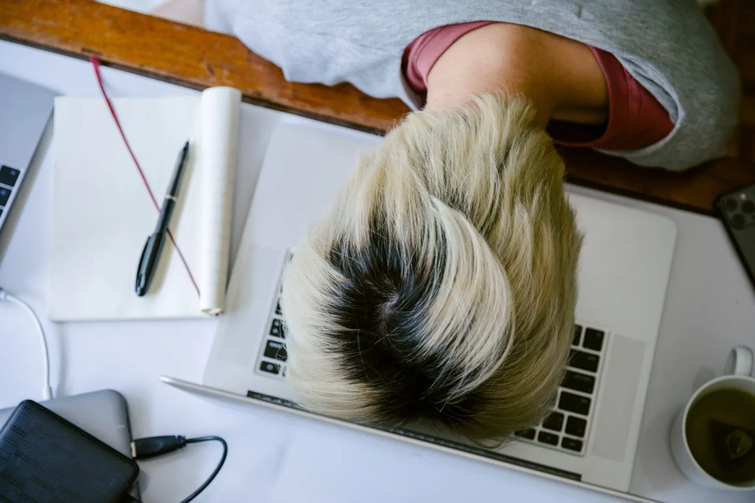Remote Work Fatigue at Desk Person slumped over laptop keyboard showing work exhaustion