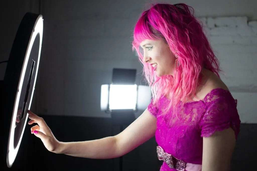 Ring Light Technique for Photo Booth Boomerangs Woman in magenta wig holding white ring light for photo booth selfie