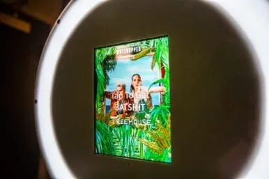 FutureFoto Ring Light Display with Treehouse Overlay Circular white ring light display showing two people with tropical Treehouse album cover green screen overlay