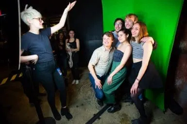 Group Event Photo with OutSnapped Green Screen Setup Group of five event attendees posing together in front of a bright green screen at Sofi Tukker's Treehouse Tour photo booth experience