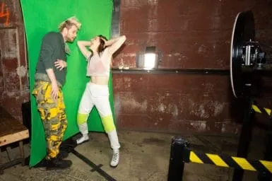 Crowd Engagement at FutureFoto Photo Booth Event Two guests pose playfully in front of bright green backdrop at OutSnapped photo booth on Sofi Tukker's Treehouse Tour, with one wearing vibrant patterned pants