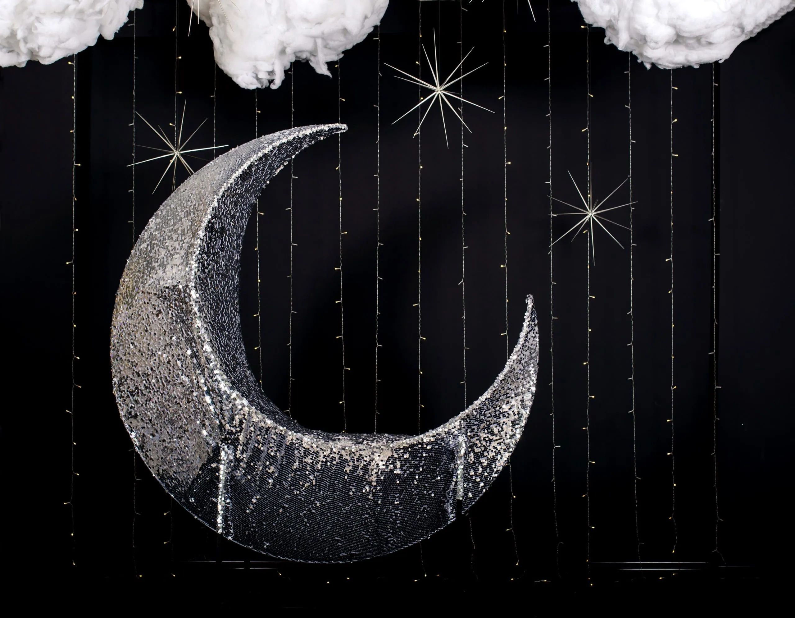 Elegant Moon & Stars Photo Booth Backdrop Sparkling silver crescent moon backdrop with hanging fairy lights and fluffy white clouds against black background, ideal for photo booth events