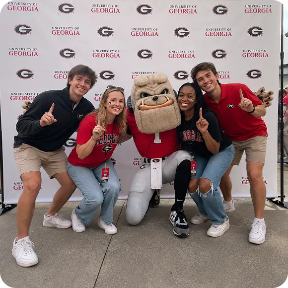 University of Georgia students with Uga mascot posing at white circular mirror photo booth