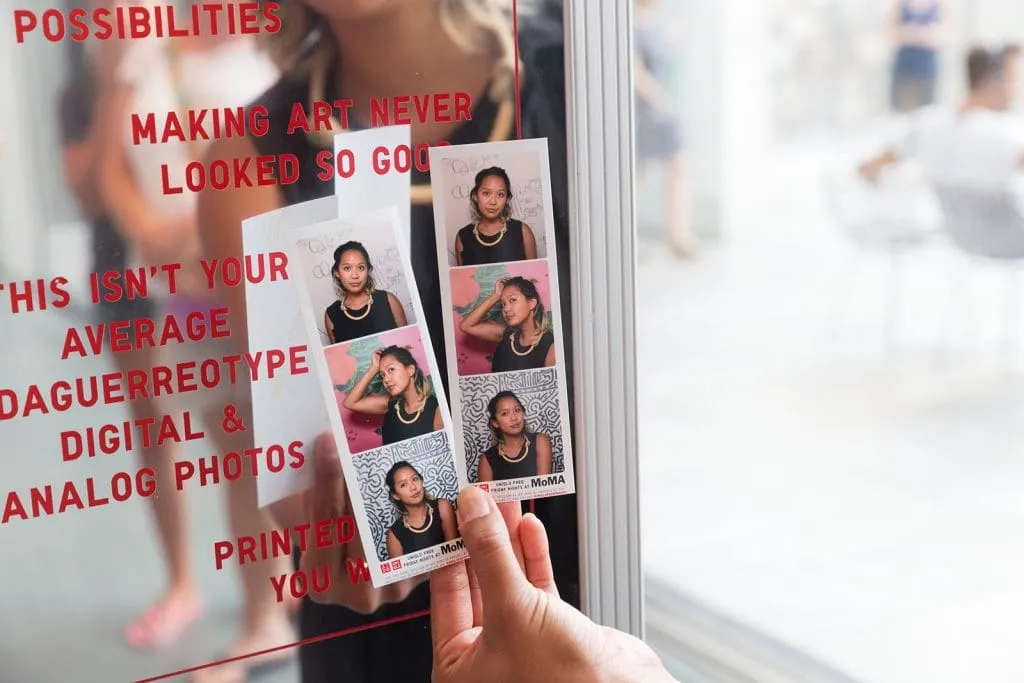 UNIQLO × MoMA Branded Photo Booth Installation Person holding photo booth strips in front of branded MagBooth mirror booth