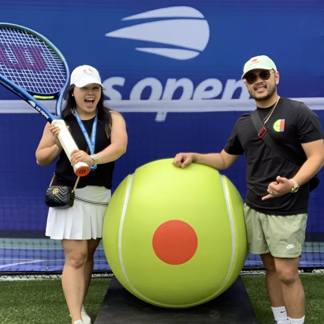US Open Pregame Stadium Photo Booth Activation Two fans posing with a giant tennis ball at a US Open branded photo booth activation inside the stadium