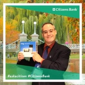 Male attendee holding business card in front of scenic garden virtual background