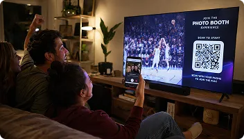 Digital Photo Sharing Experience at Home Two people viewing a digital screen displaying a photo booth QR code and event imagery during a virtual photo booth experience