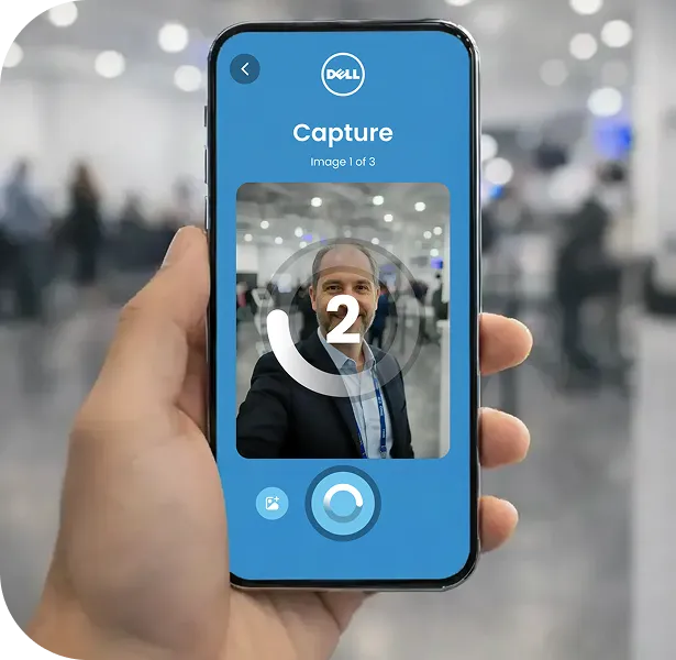 AI Photo Booth Mobile Capture Interface Person holding smartphone displaying virtual photo booth capture interface with blue UI showing image 1 of 3, Dell logo, and shutter button
